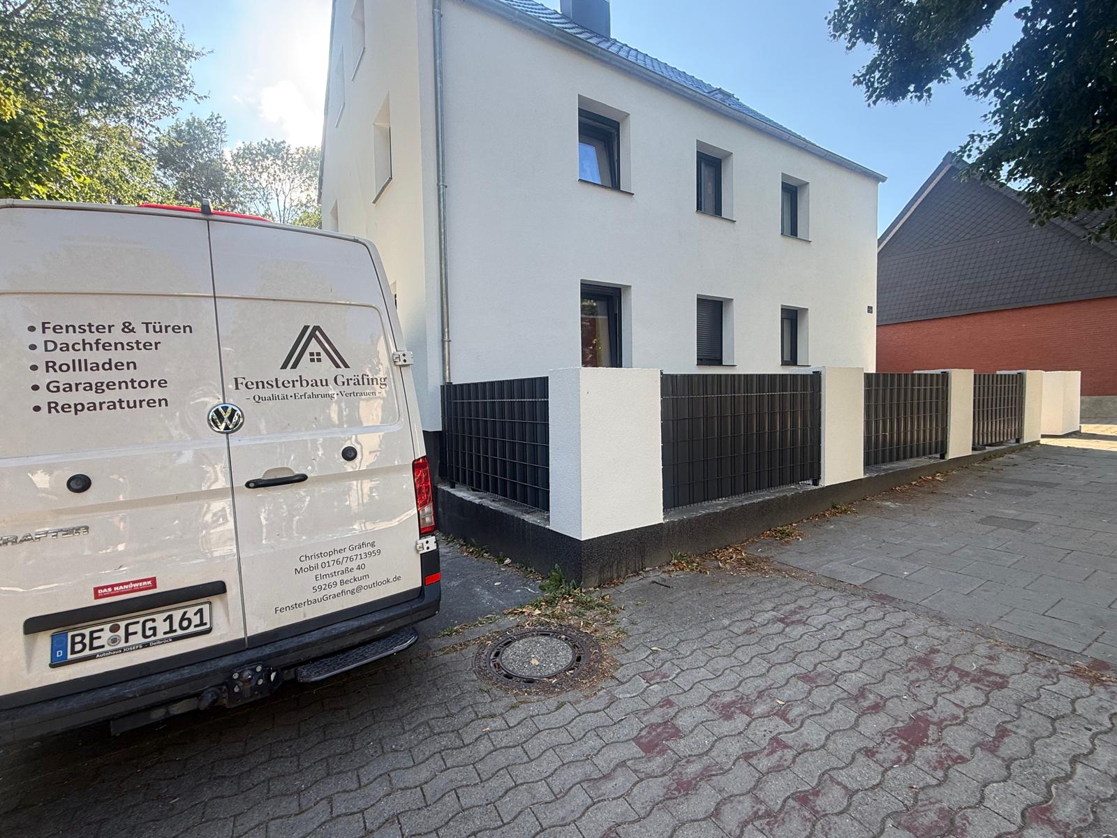 Heck des Firmenwagens von Fensterbau Gräfing vor einem weißen Haus mit dunklen Fenstern