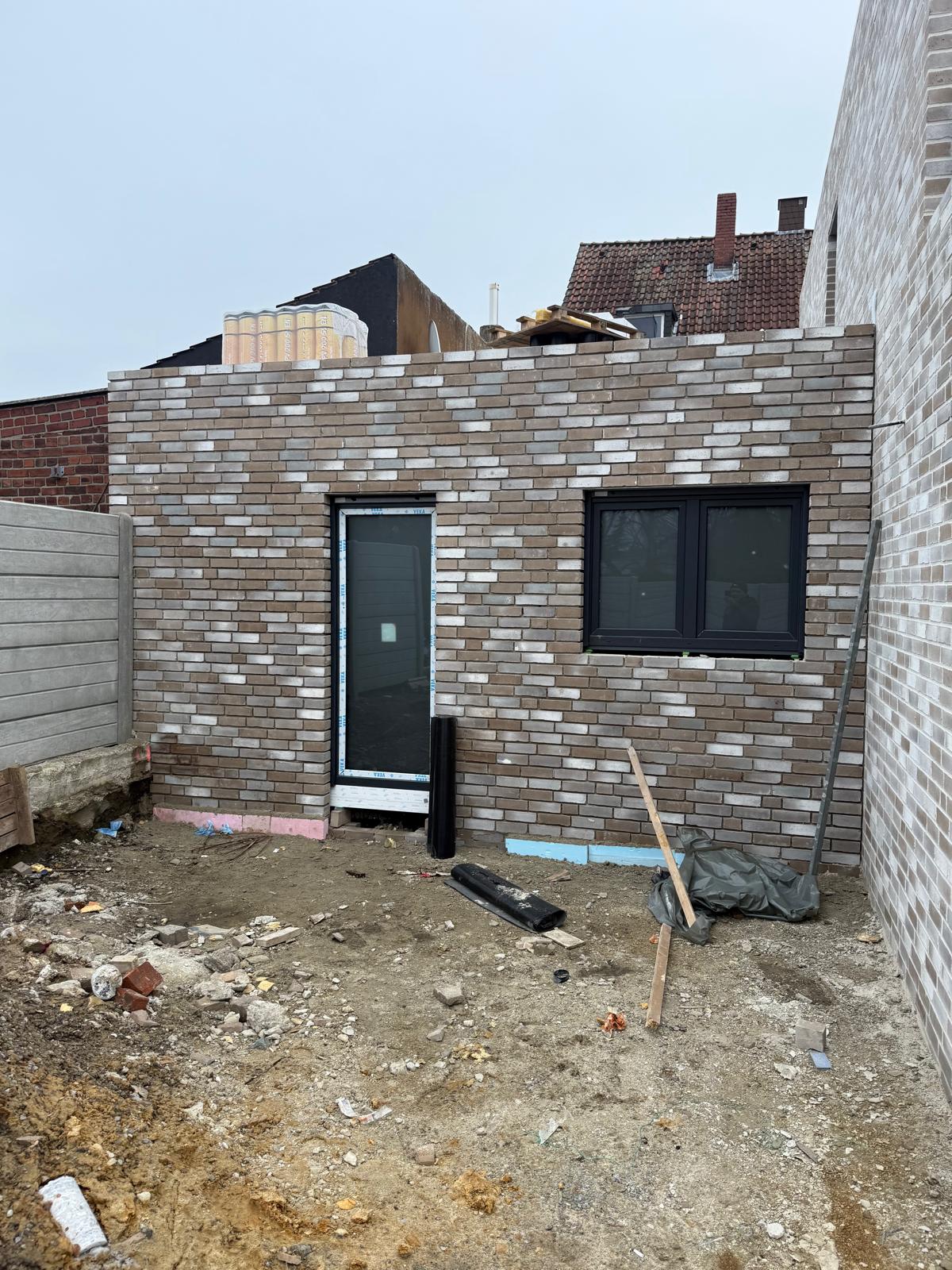 Klinkeranbau im Rohbau mit neu eingesetzter Tür und dunklem Fenster