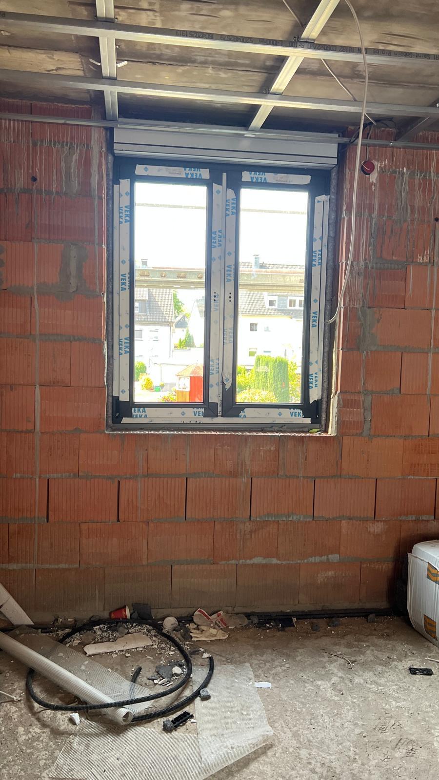 Zweiflügeliges Fenster mit Rollladenkasten in einer unverputzten Ziegelwand