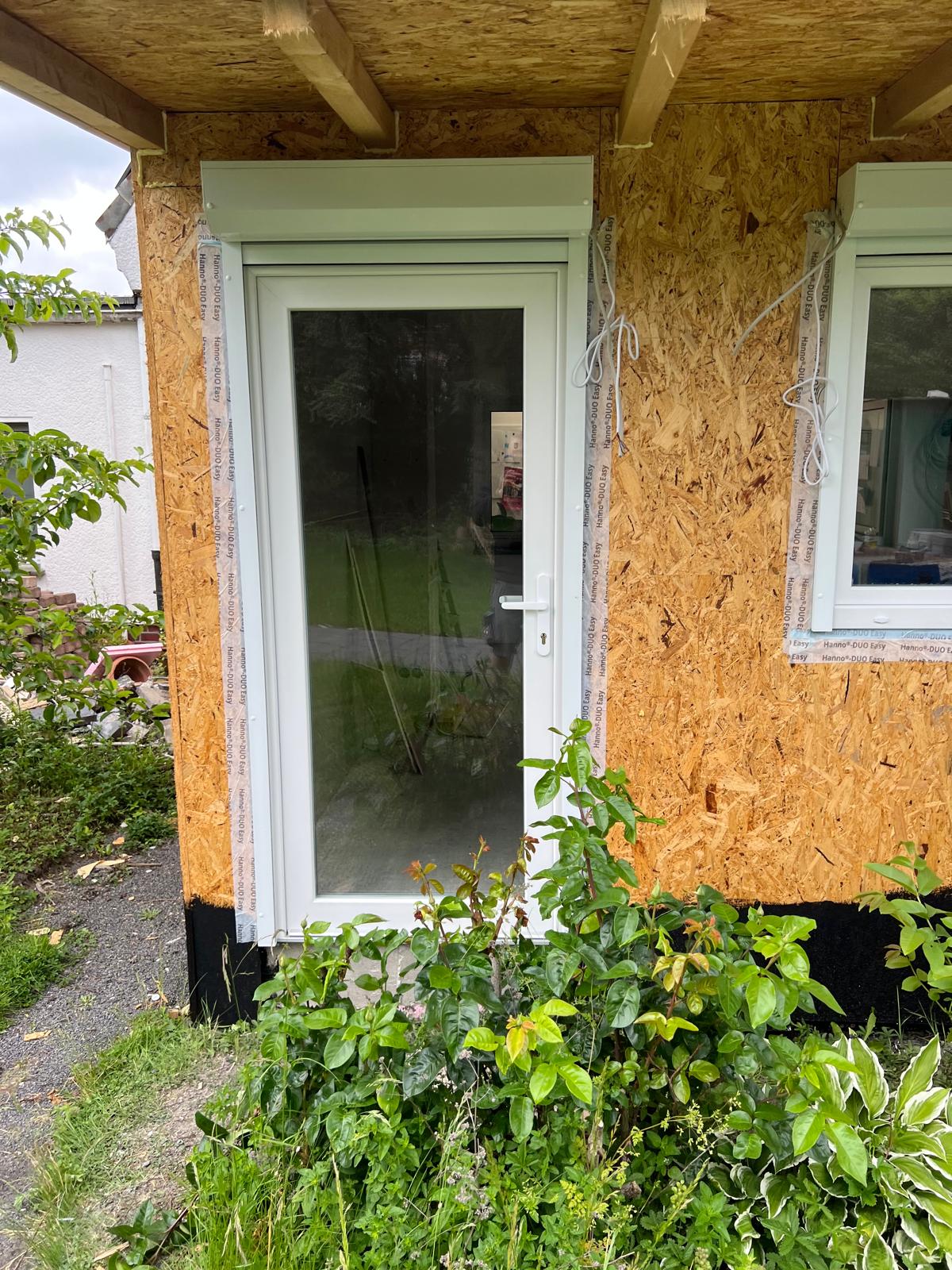 Weiße Glastür mit Rollladenkasten in einer noch unverkleideten Holzwand