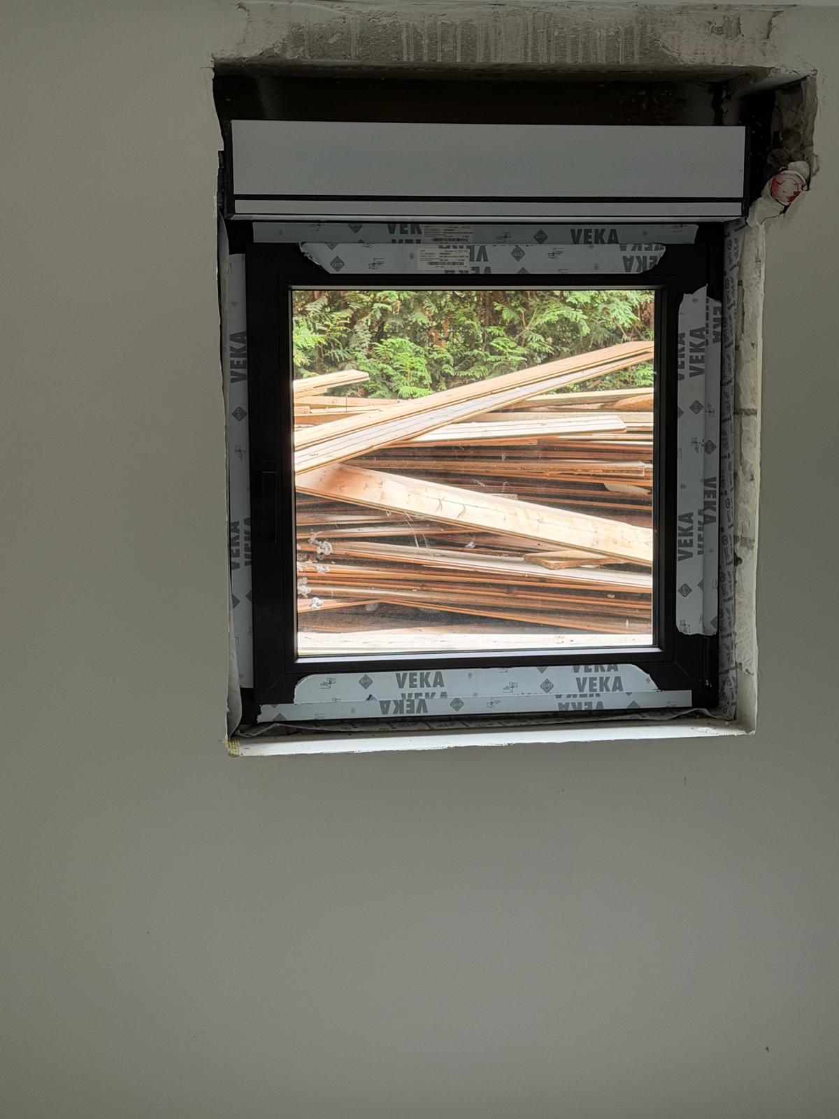 Neu eingebautes kleines Fenster mit Rollladenkasten in einer frisch verputzten Wand