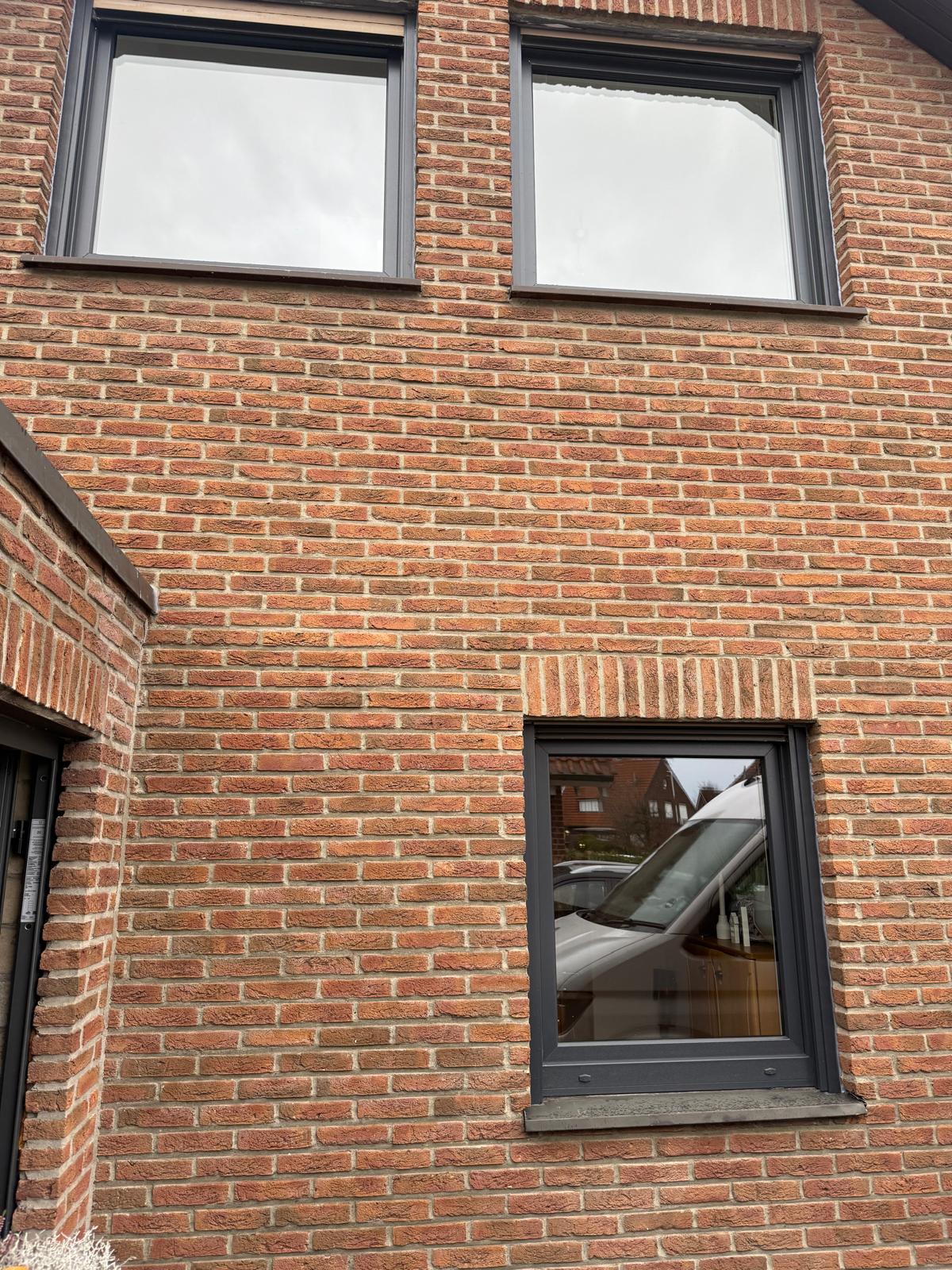 Rote Klinkerfassade mit drei anthrazitfarbenen Fenstern