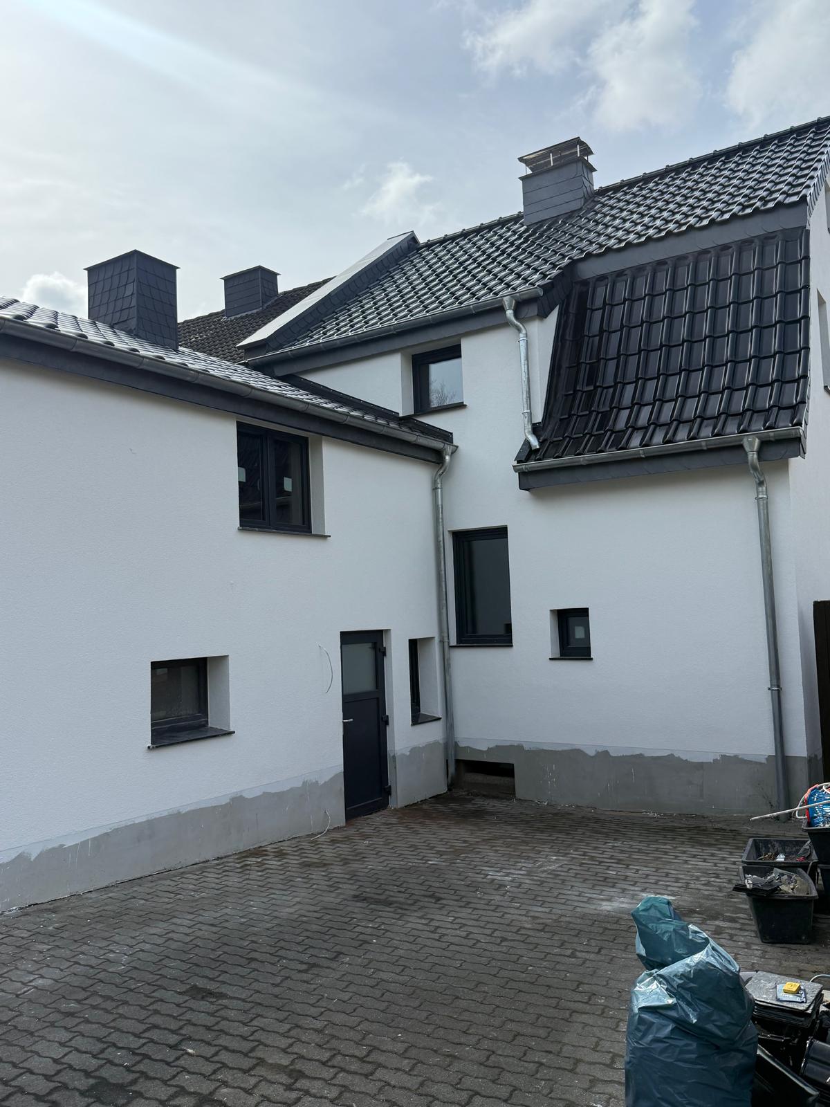 Weiße Hoffassaden mit dunklen Fenstern, Fallrohren und dunkel gedecktem Dach
