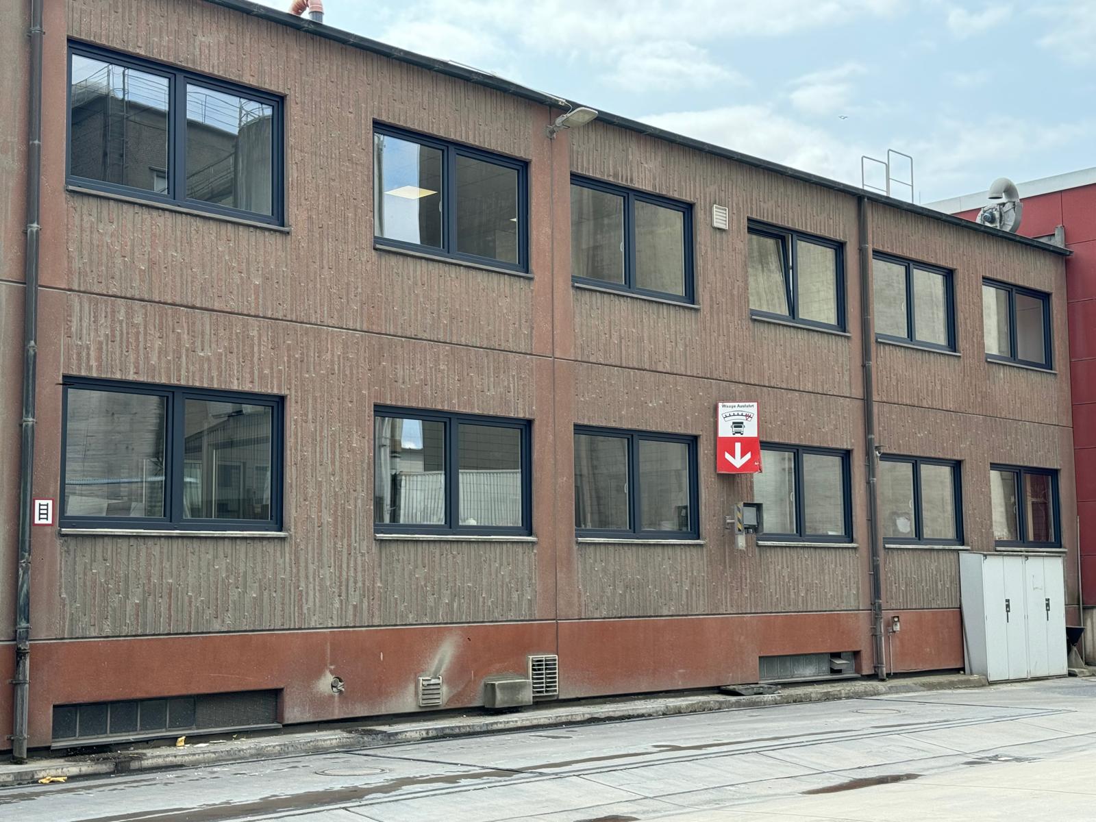 Zweigeschossiger Gewerbebau mit rotbrauner Fassade und gleichmäßig gereihten, dunkel gerahmten Fenstern