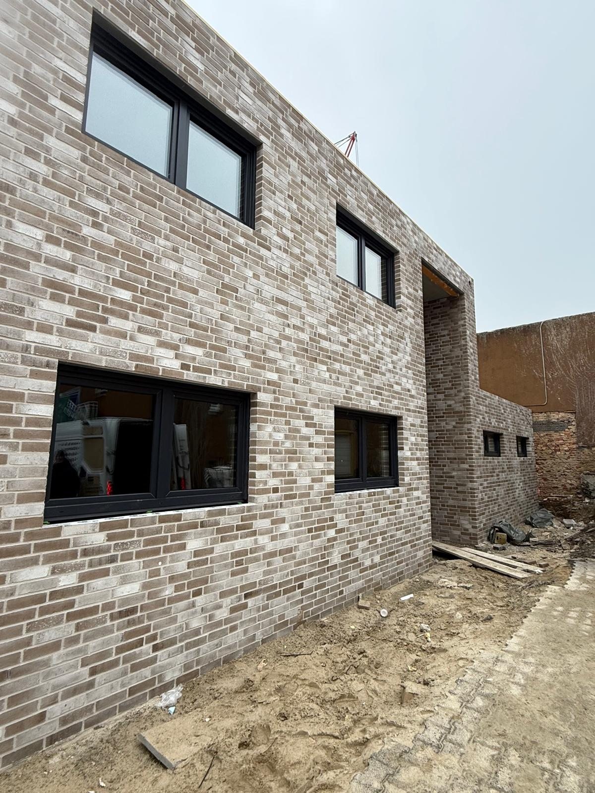 Neubau mit grauer Klinkerfassade und liegenden, dunkel gerahmten Fenstern